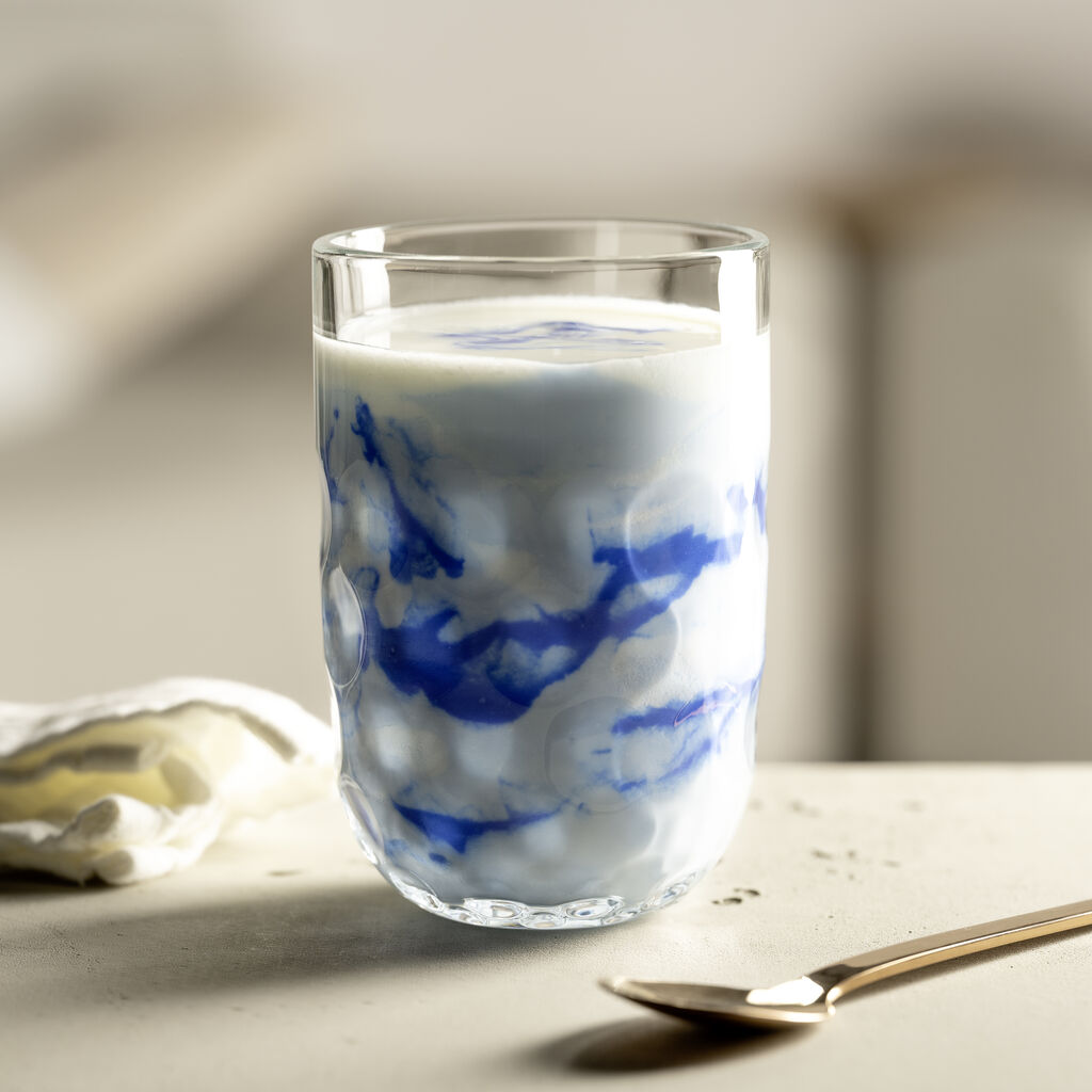 LEONARDO Kafeeglas mit strukturierter Oberfläche, gefüllt mit cremigem blau-weißem Smoothie, daneben goldfarbener Löffel.