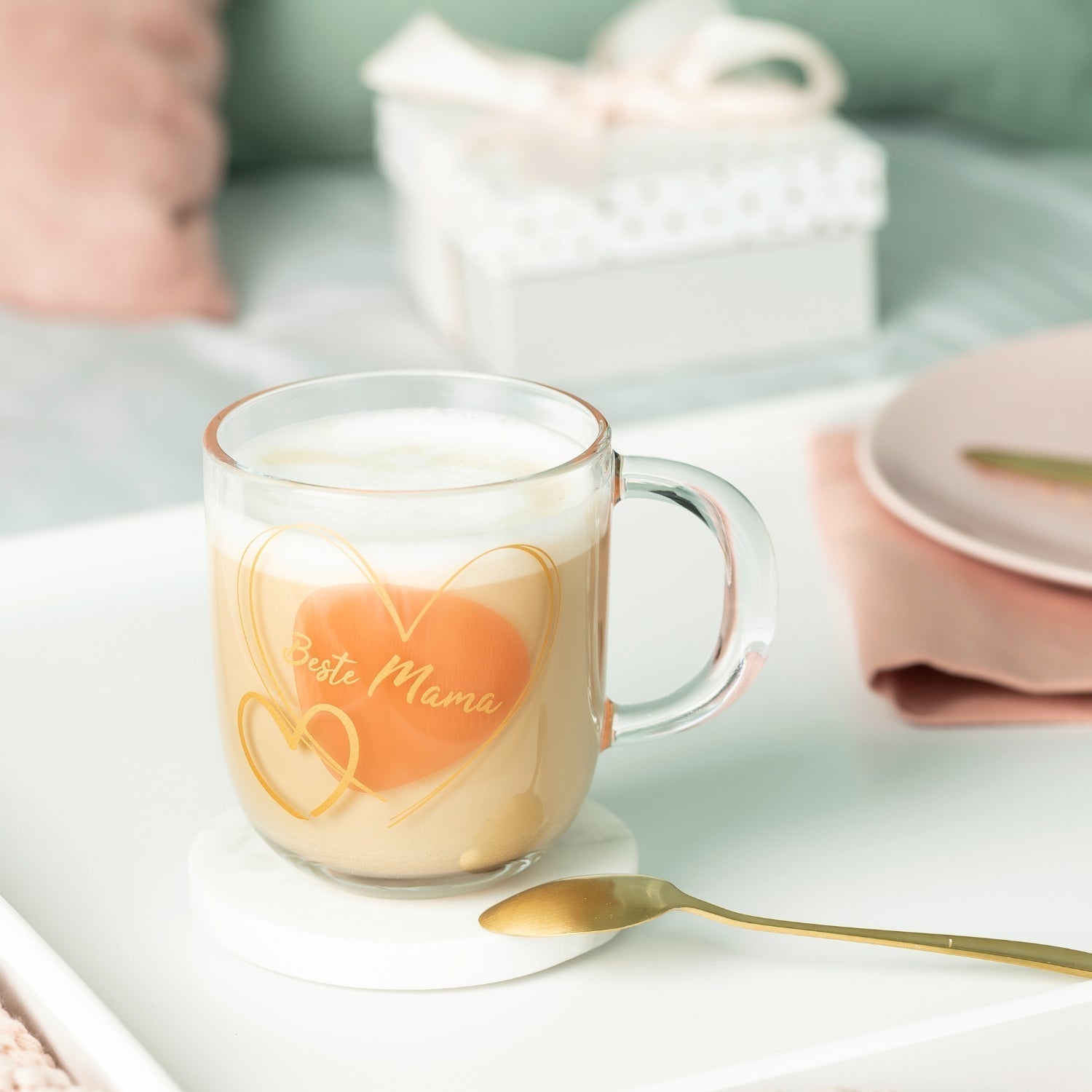 LEONARDO Kaffeeglas mit goldfarbenem Herzmotiv und Aufschrift „Beste Mama“ auf einem weißen Frühstückstablett.