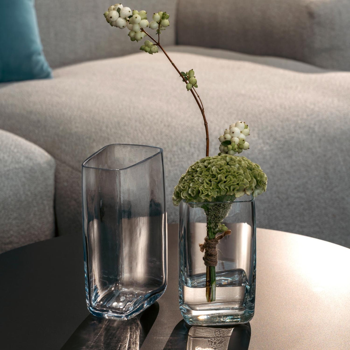 Vase PIETRA mit grünen Blüten in Wohnzimmer auf Tisch neben leerem Glas