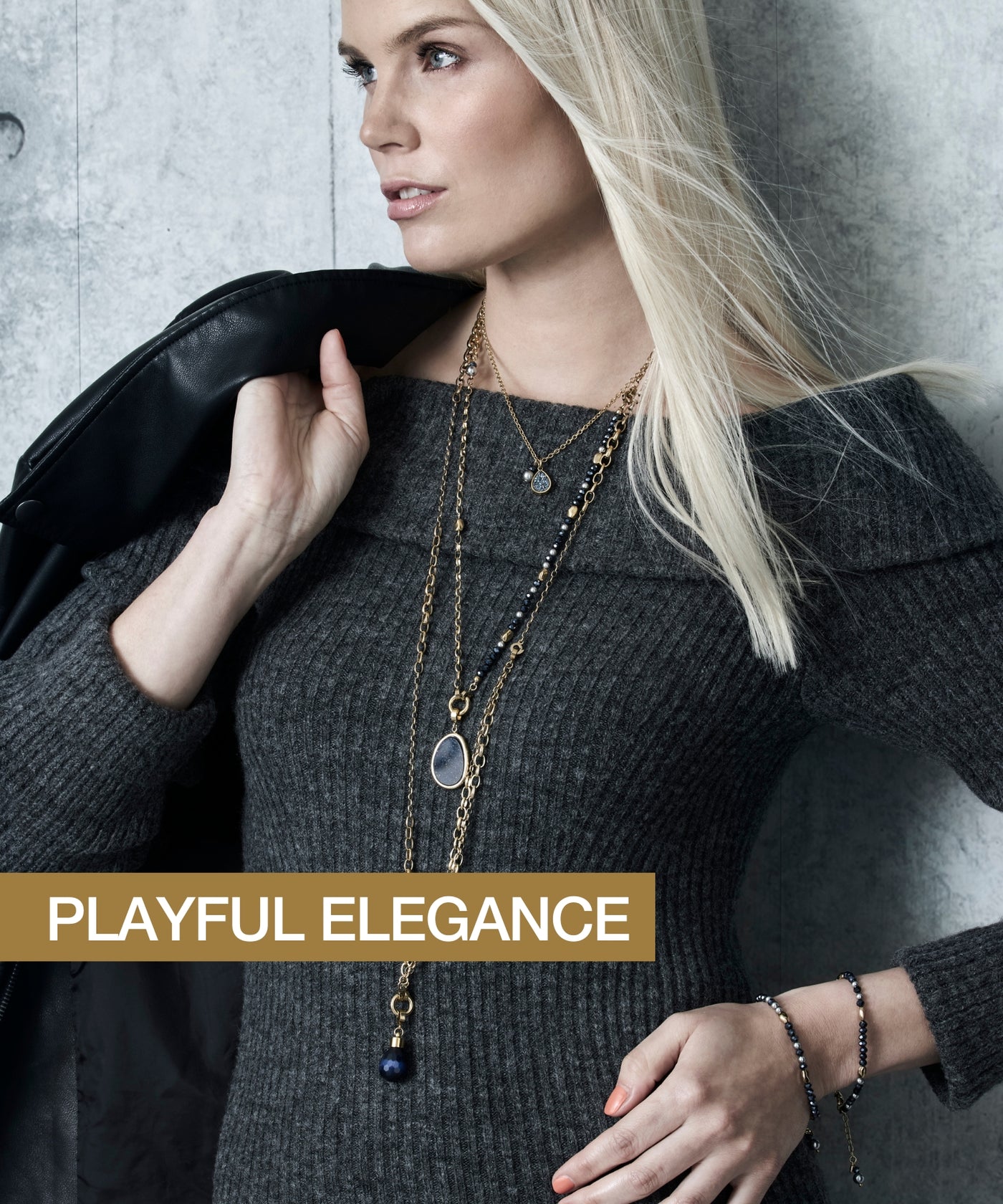Eine Frau im grauen Strickkleid kombiniert goldene Ketten mit blauen Details sowie passende Armbänder – der Look wird mit dem Claim „PLAYFUL ELEGANCE“ betont.