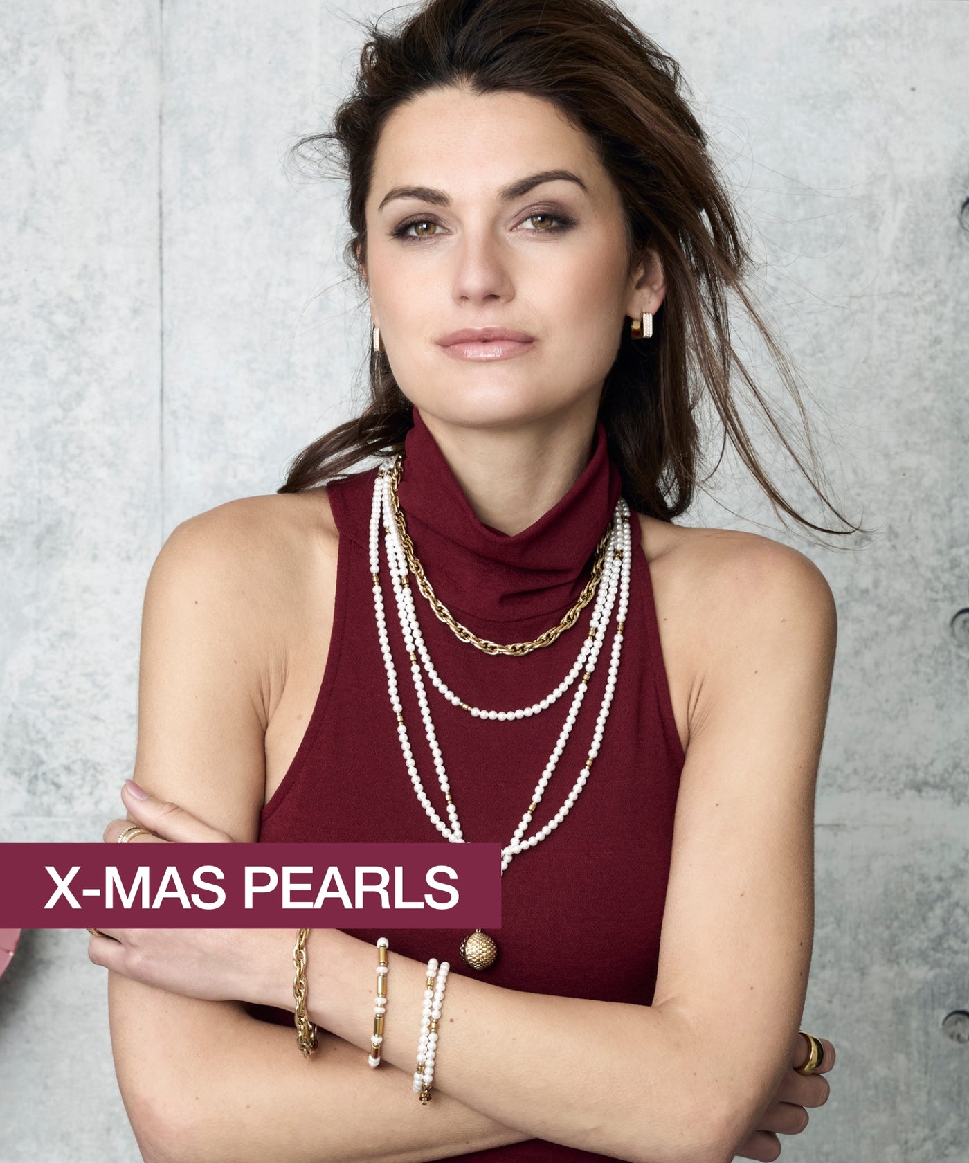 Eine Frau in einem bordeauxfarbenen Top trägt mehrreihige Perlenketten, goldene Armbänder und Ohrringe – der Text „X-MAS PEARLS“ unterstreicht den festlichen Look.