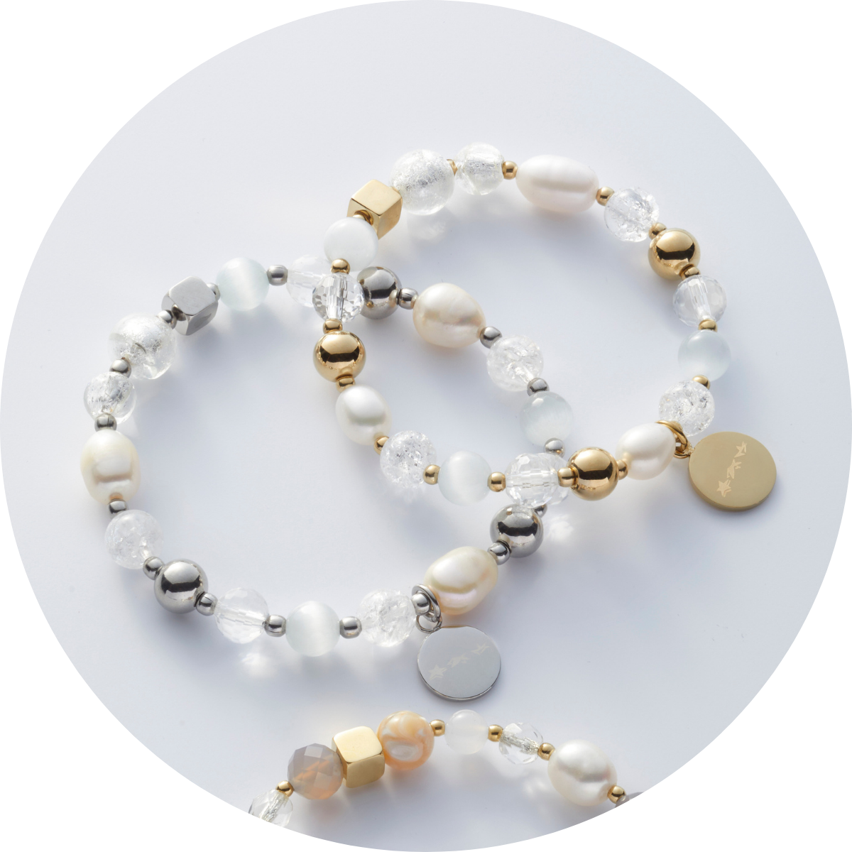 Zarte Armbänder mit Perlen und schimmernden Details in Gold, Silber und Weiß auf hellem Hintergrund.