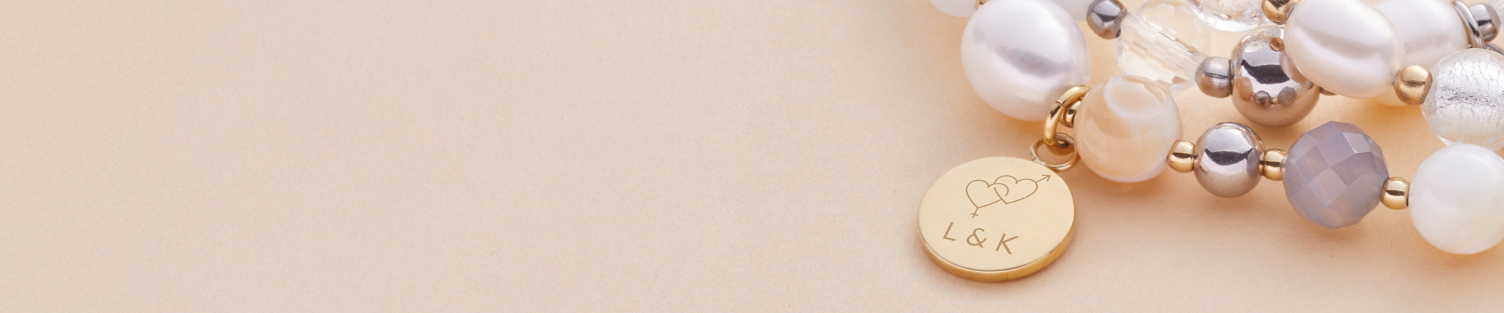 Armband HOPE mit Gravur. "L & K" steht dadrauf sowie ein Symbol, welches zwei ineinander verschlungene Herzen zeigt sowie das Zeichen für Männlich und Weiblich