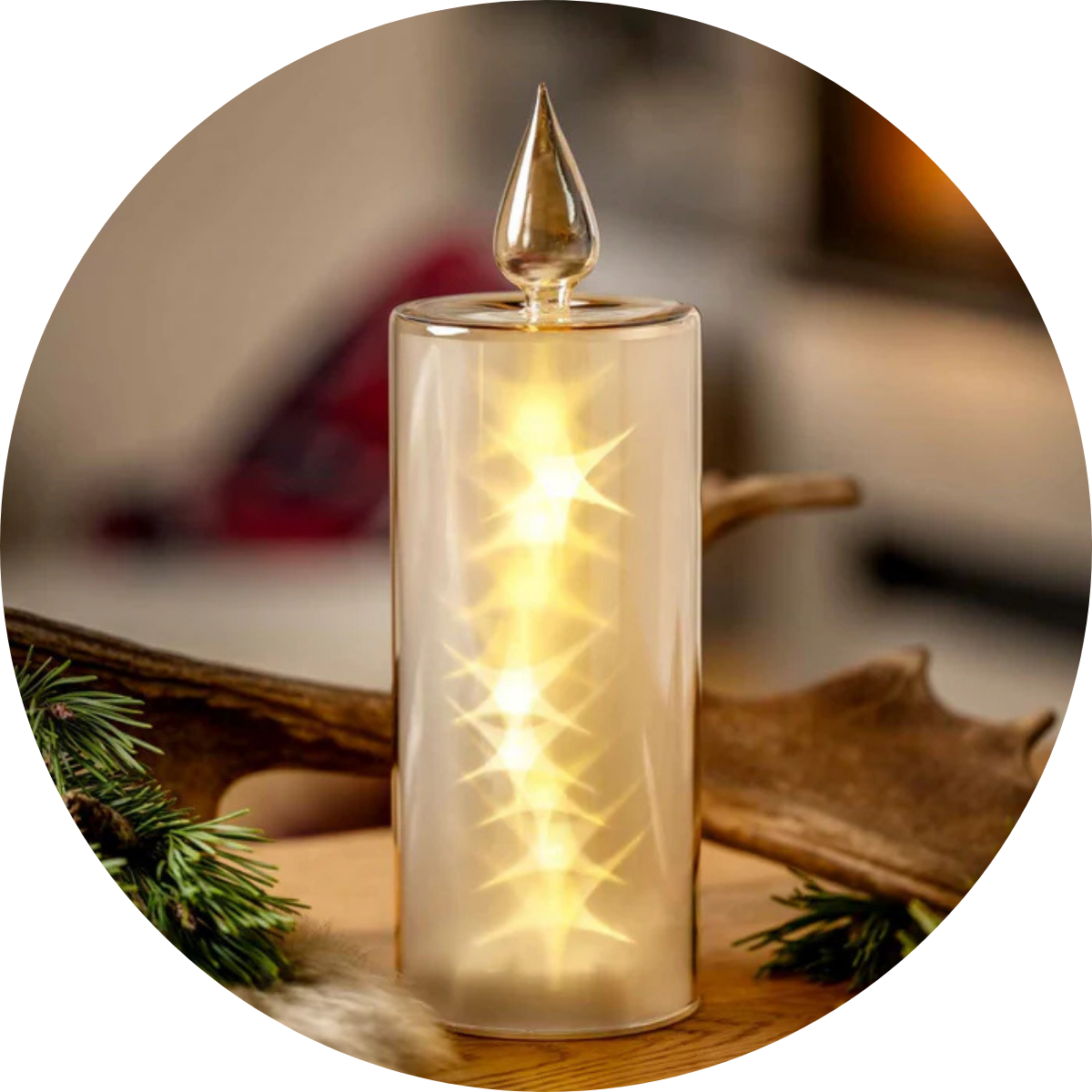 Goldfarbene LED-Leuchte mit Tropfenaufsatz auf einem Holztisch, erzeugt ein warmes, sternenförmiges Lichtmuster.