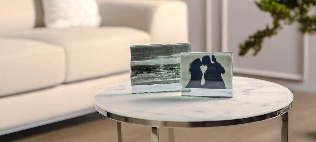 Glassrahmen mit Fotos auf Marmortisch, helles Wohnzimmer mit Sofa im Hintergrund