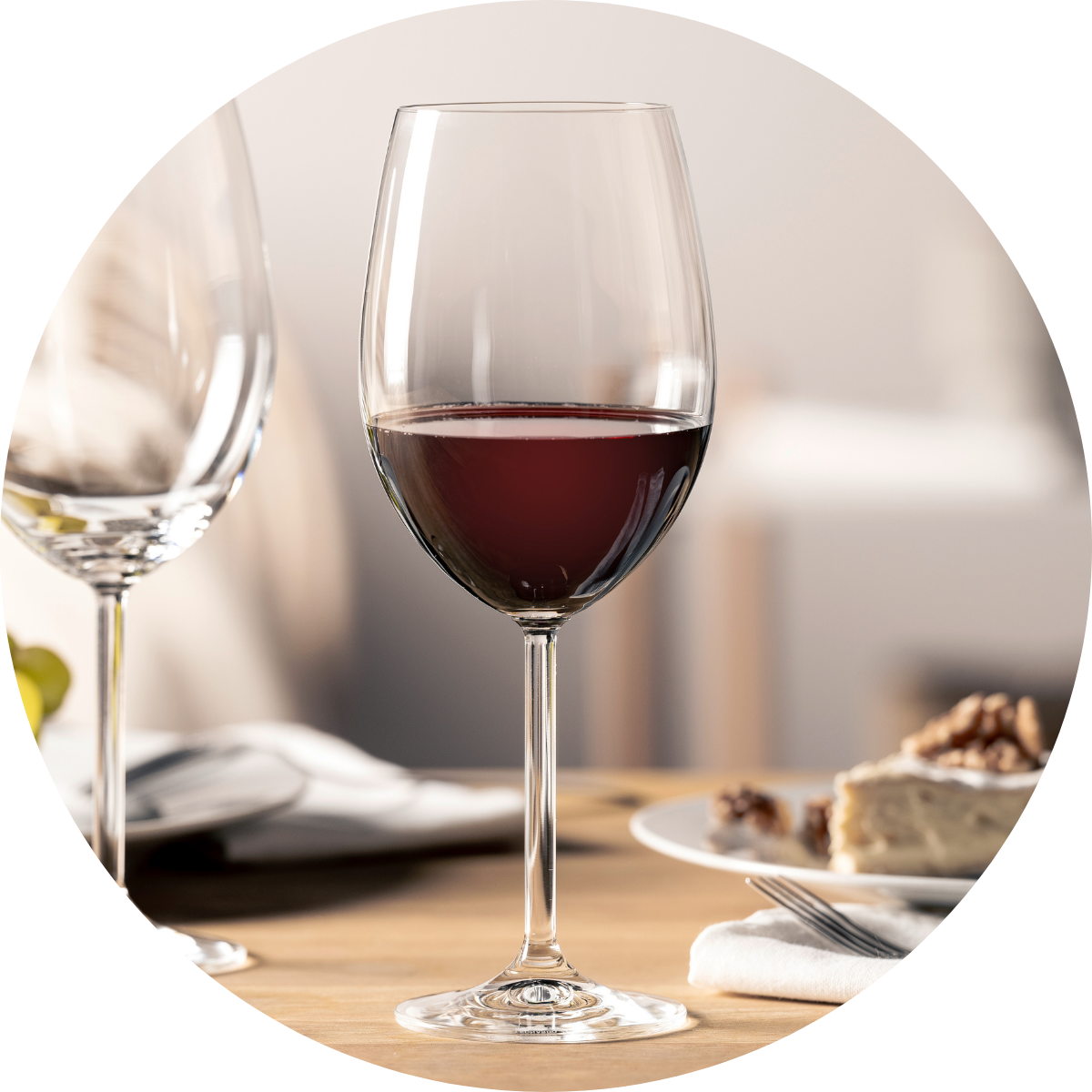 Bordeauxglas mit Rotwein auf gedecktem Tisch.