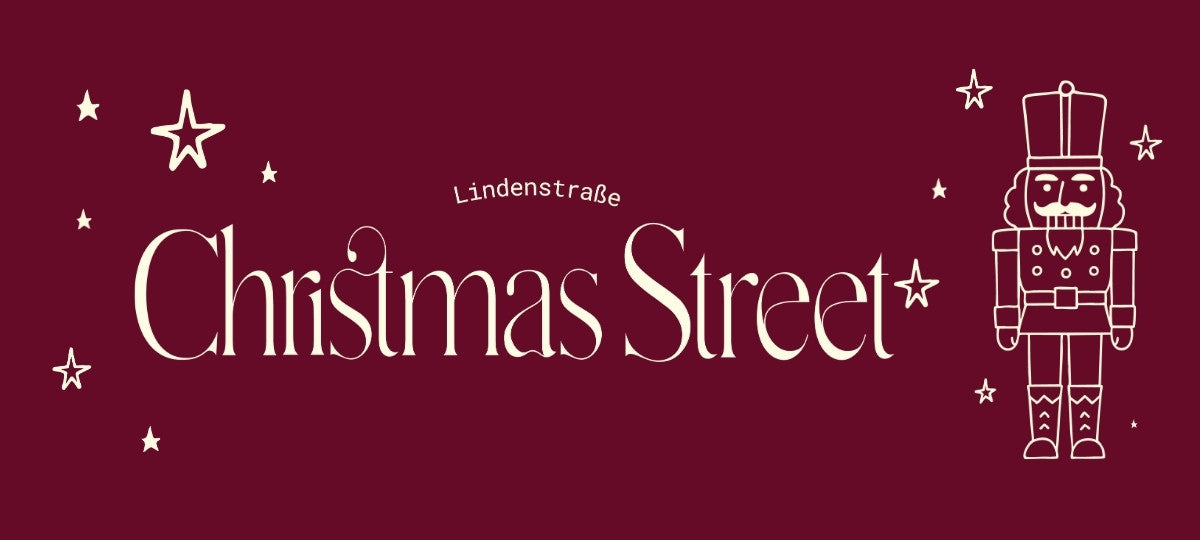 Grafisches Banner mit burgunderrotem Hintergrund. In der Mitte steht der Schriftzug ‚Christmas Street‘ in dekorativer, cremefarbener Schrift, darüber klein ‚Lindenstraße‘. Um den Text sind gezeichnete Sterne verteilt. Rechts steht eine stilisierte cremefarbene Nussknacker-Figur.