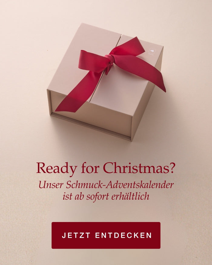 Ready for Christmas? Schmuck-Adventskalender ab sofort erhältlich. Creme-farbene Geschenkbox mit rotem Samtband auf hellem Hintergrund