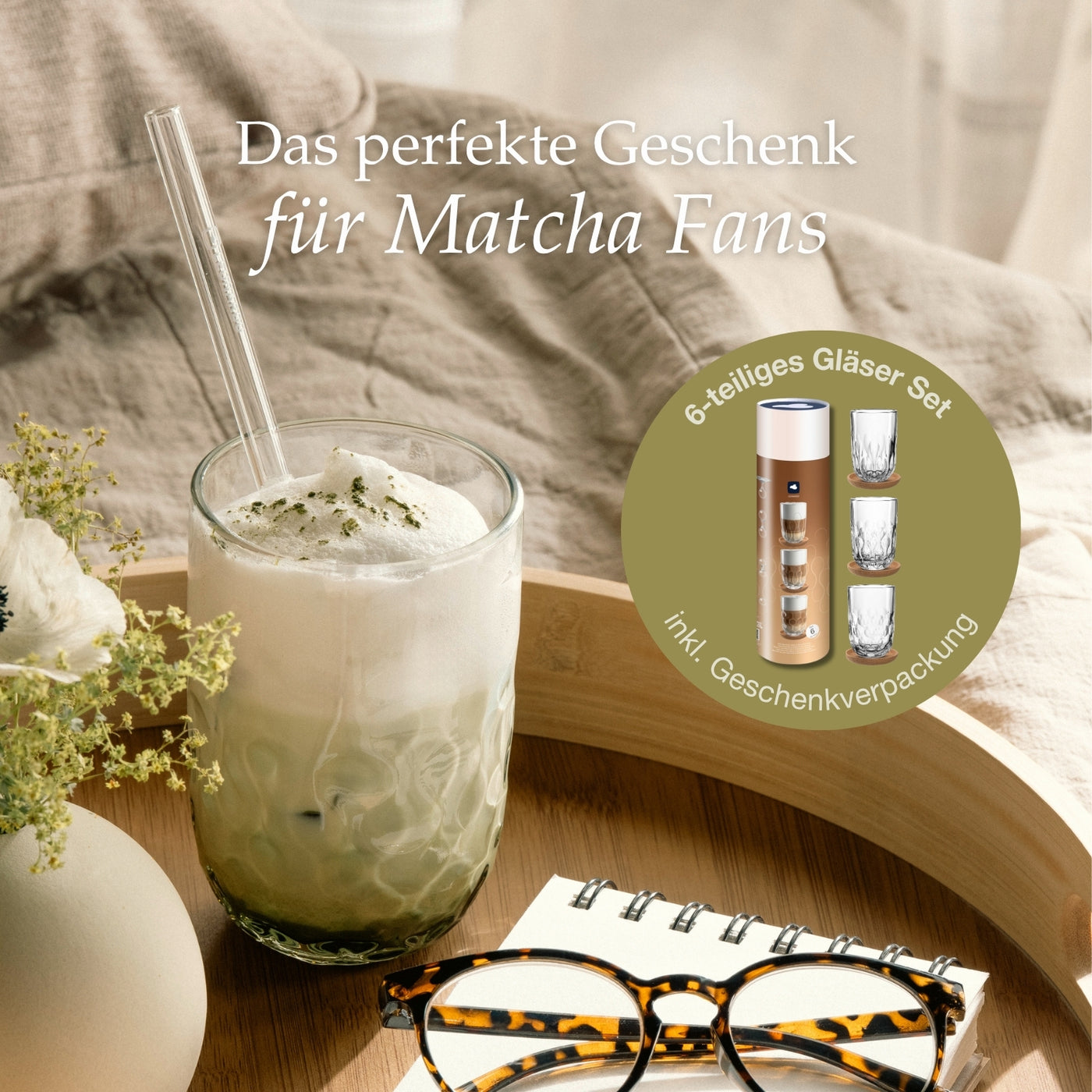 Glas Matcha Latte mit Milchschaum und Glastrinkhalm auf einem Holztablett, daneben eine Vase mit Blumen, eine Brille und ein Notizbuch – beworben als 6-teiliges Gläserset in Geschenkverpackung mit dem Text „Das perfekte Geschenk für Matcha Fans“.