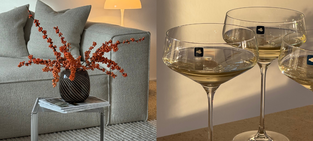 Wohnszene mit grauem Sofa und Beistelltisch, darauf eine dunkle Vase mit roten Beerenzweigen; daneben ein Schwarz-Weiß-Porträt einer Frau.