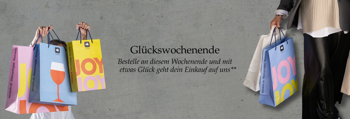 Glückswochenende. Bunte Einkaufstaschen mit JOY-Motiven, Hände halten Tüten, grauer Hintergrund, Einkaufsszene
