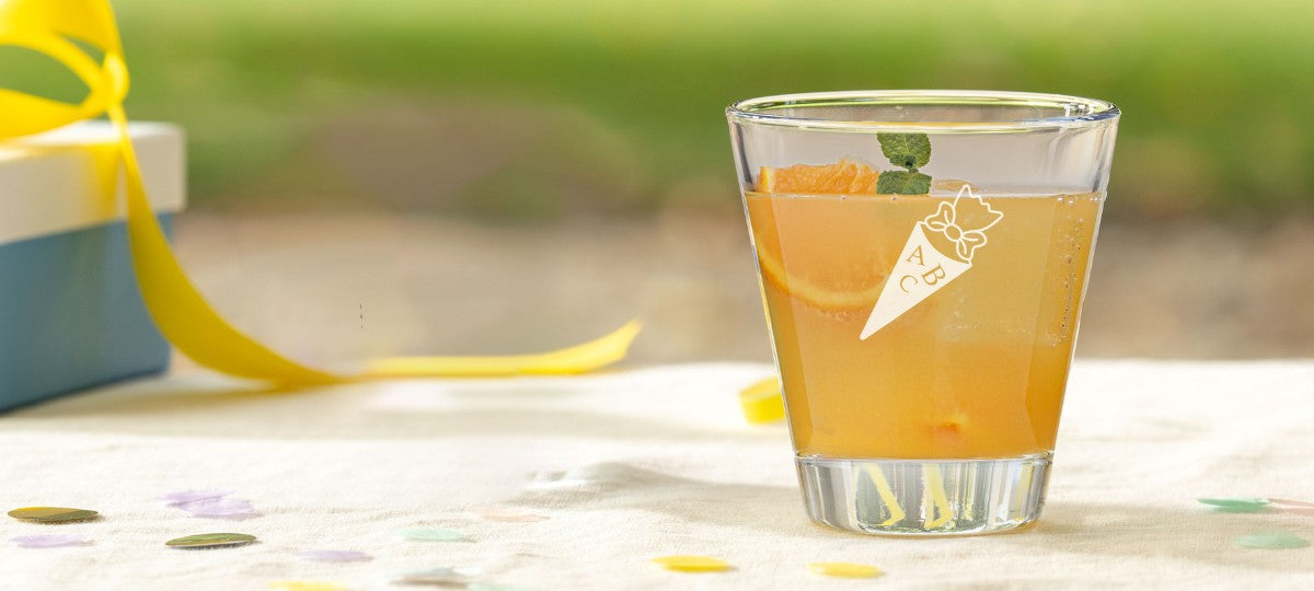 Trinkglas von LEONARDO mit eingravierter Schultüte und ABC-Motiv, dekorativ angerichtet mit Orangenscheiben und Minze.