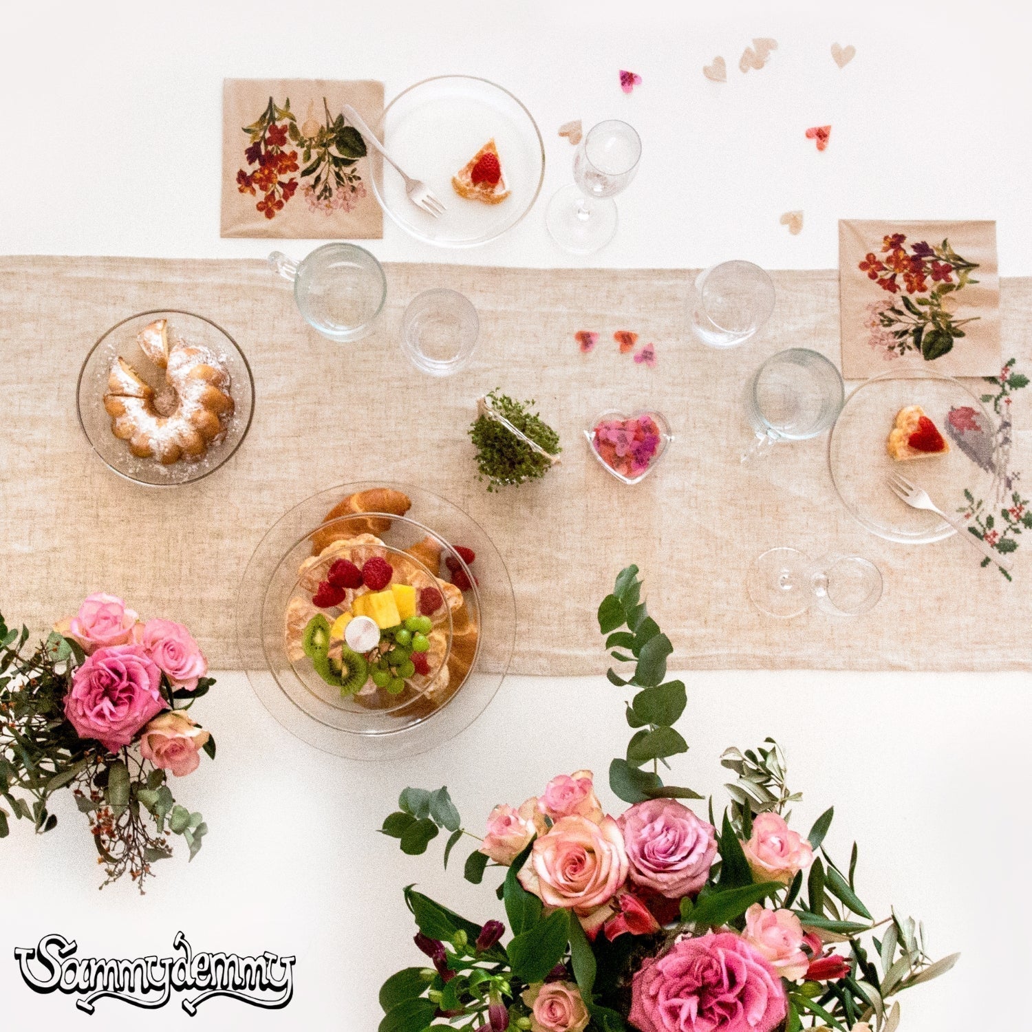 Eine festlich gedeckte Tafel mit Glasgeschirr, Blumen und süßem Gebäck in Herzform, ideal für einen romantischen Anlass