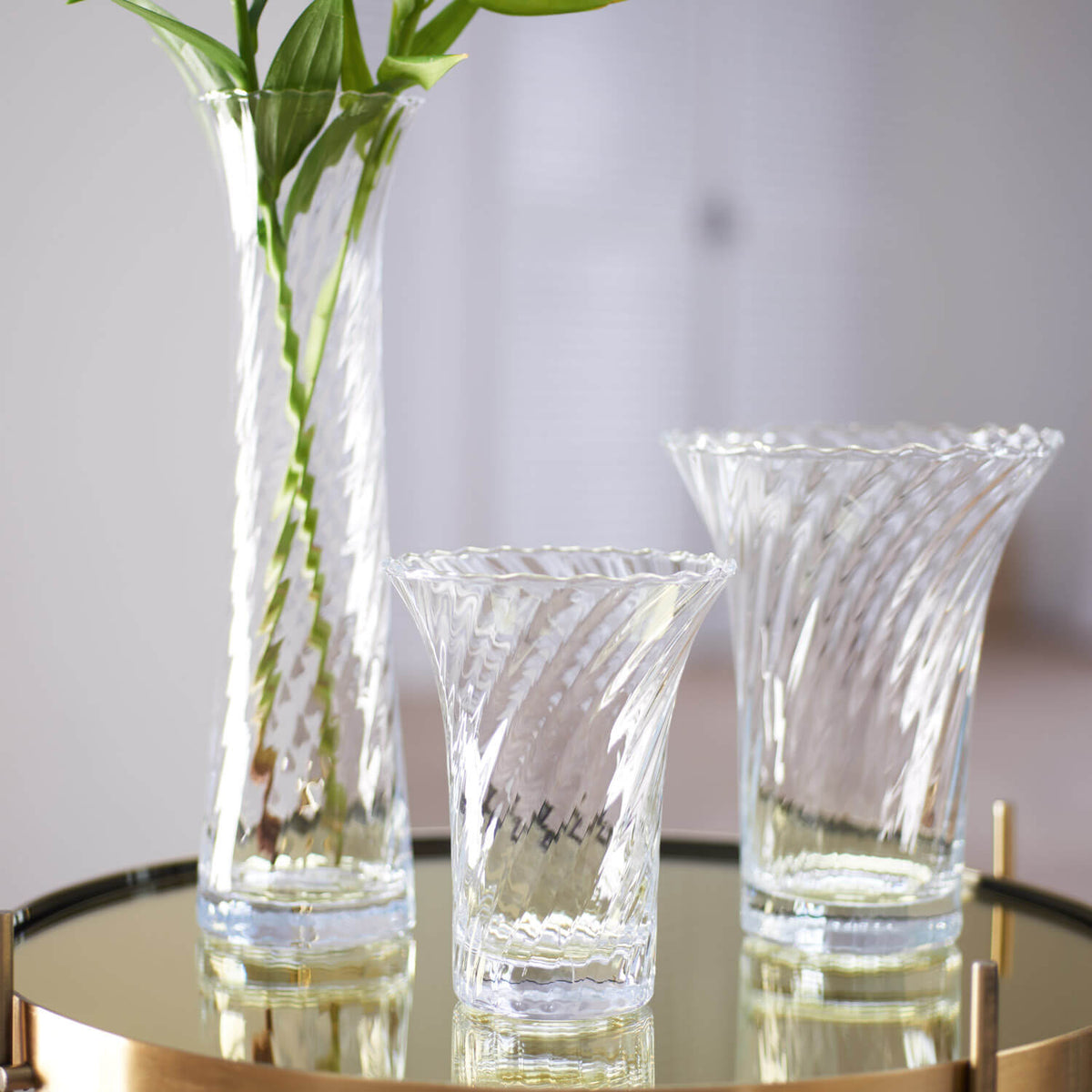 Vase RAVENNA mit Blumen auf Glastisch, daneben zwei Gläser