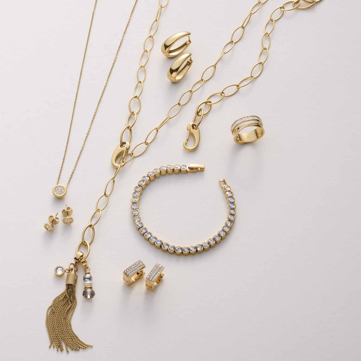 Goldene Schmuckkollektion mit Halsketten, Armbändern, Ringen und Ohrringen auf weißem Hintergrund