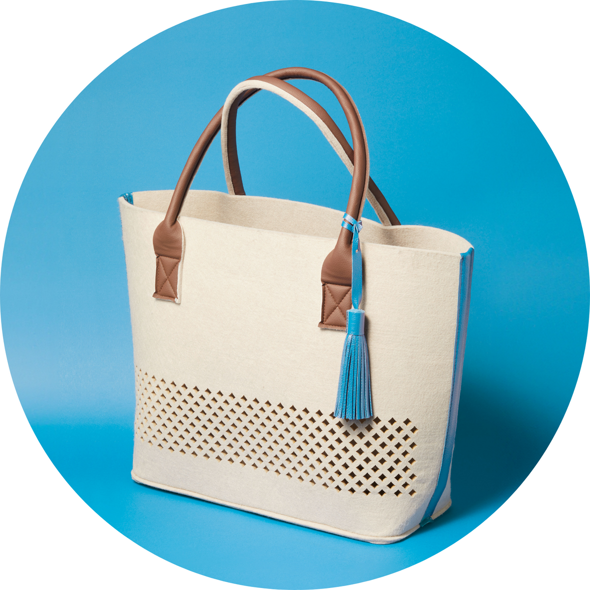 LEONARDO Beach Bag beige Papiertragetasche mit braunen Henkeln und blauem Quastenverzierung auf blauem Hintergrund