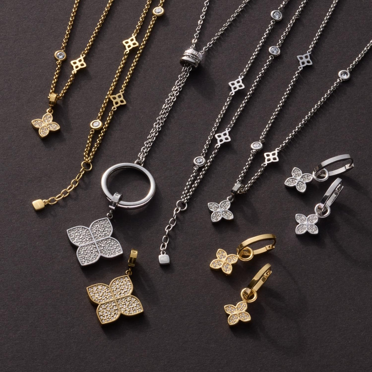 Schmuckkollektion mit goldenen und silbernen Blütenanhängern an Ketten und Ohrringen