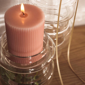 Glasdose mit brennender rosa Kerze, Dekoration auf Holztisch arrangiert