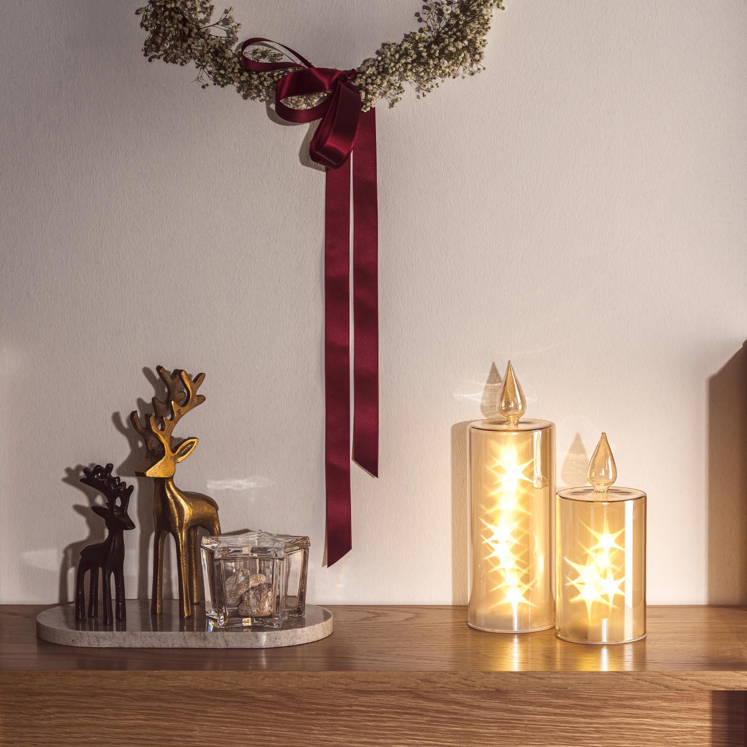 Hirsch RIPOSO 16 cm schwarz auf Tisch mit LED-Kerzen und weihnachtlicher Dekoration