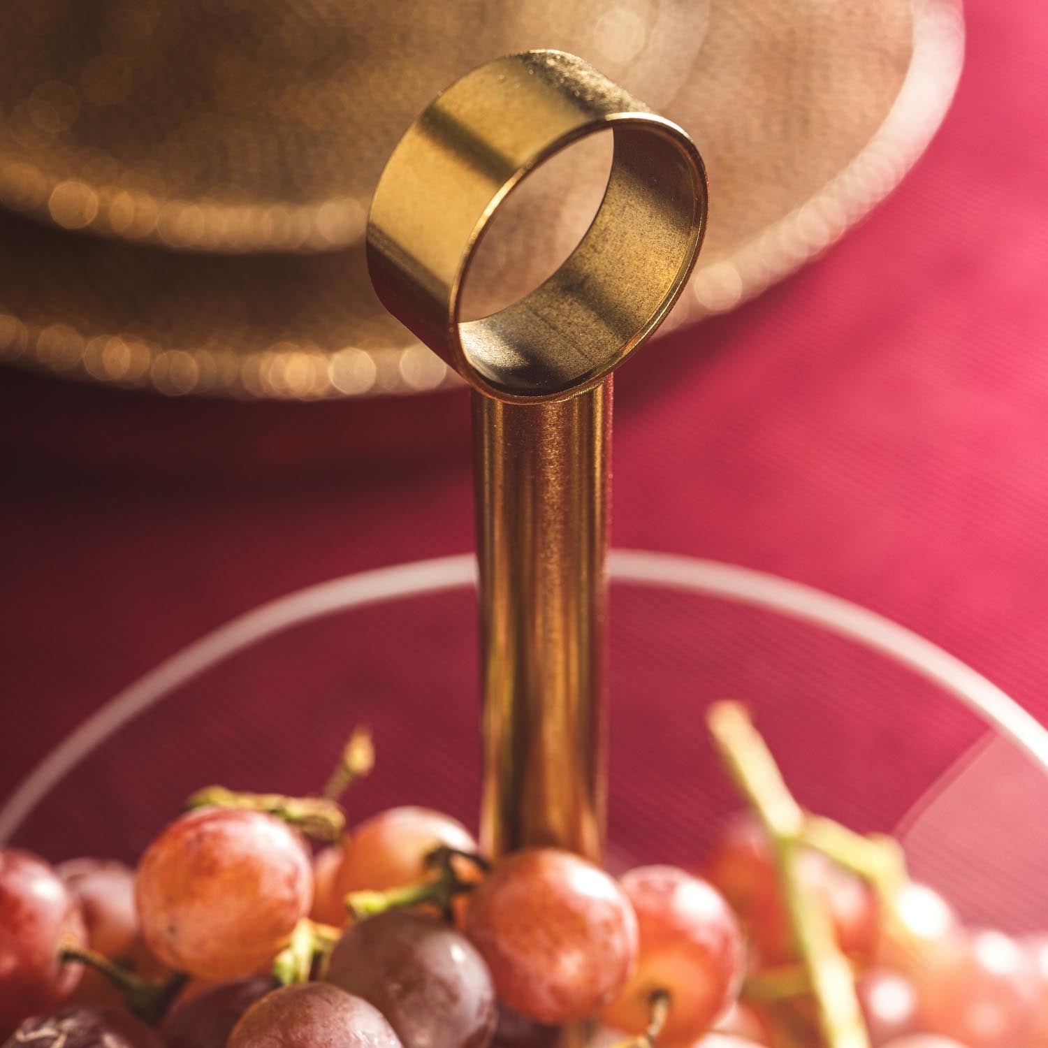Etagere CENA gold mit Weintrauben auf pinkem Hintergrund, Detailaufnahme der oberen Schale