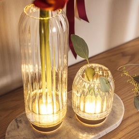 LED Vase RIPOSO mit warm leuchtenden Gläsern auf Holztisch, dekoriert mit Blättern