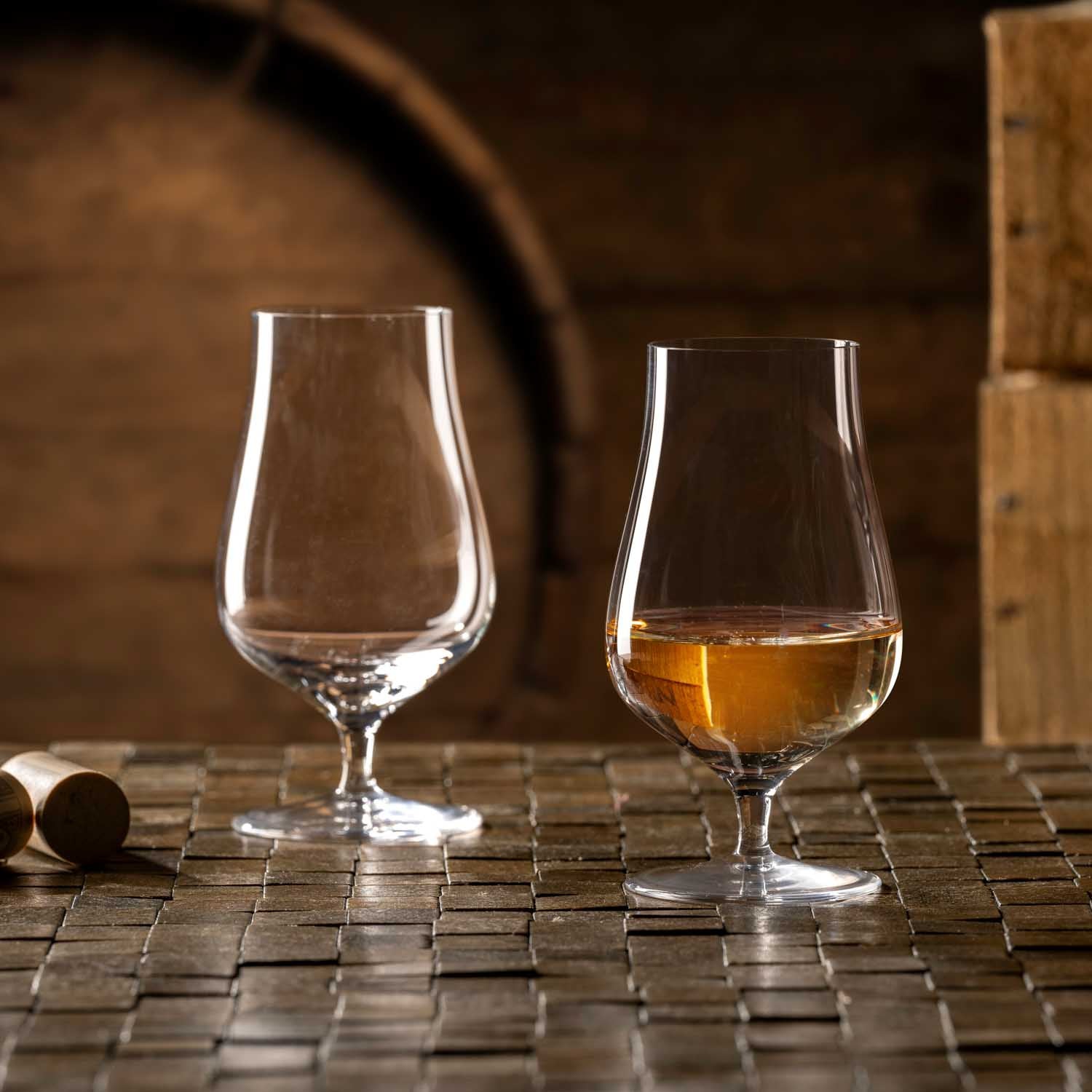 Whiskygläser BRUNELLI auf Fuß, eines leer und eines mit Whisky gefüllt, auf Holzoberfläche