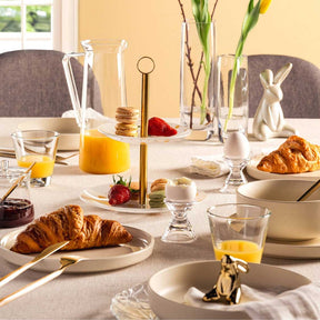 Hase LOLA auf gedecktem Frühstückstisch zwischen Croissants und Blumen