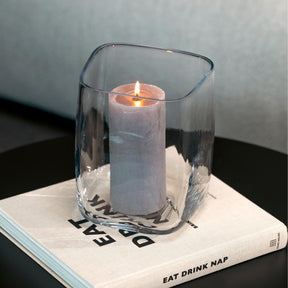 Vase/Windlicht PIETRA mit brennender Kerze auf Buch, Stillleben-Anordnung