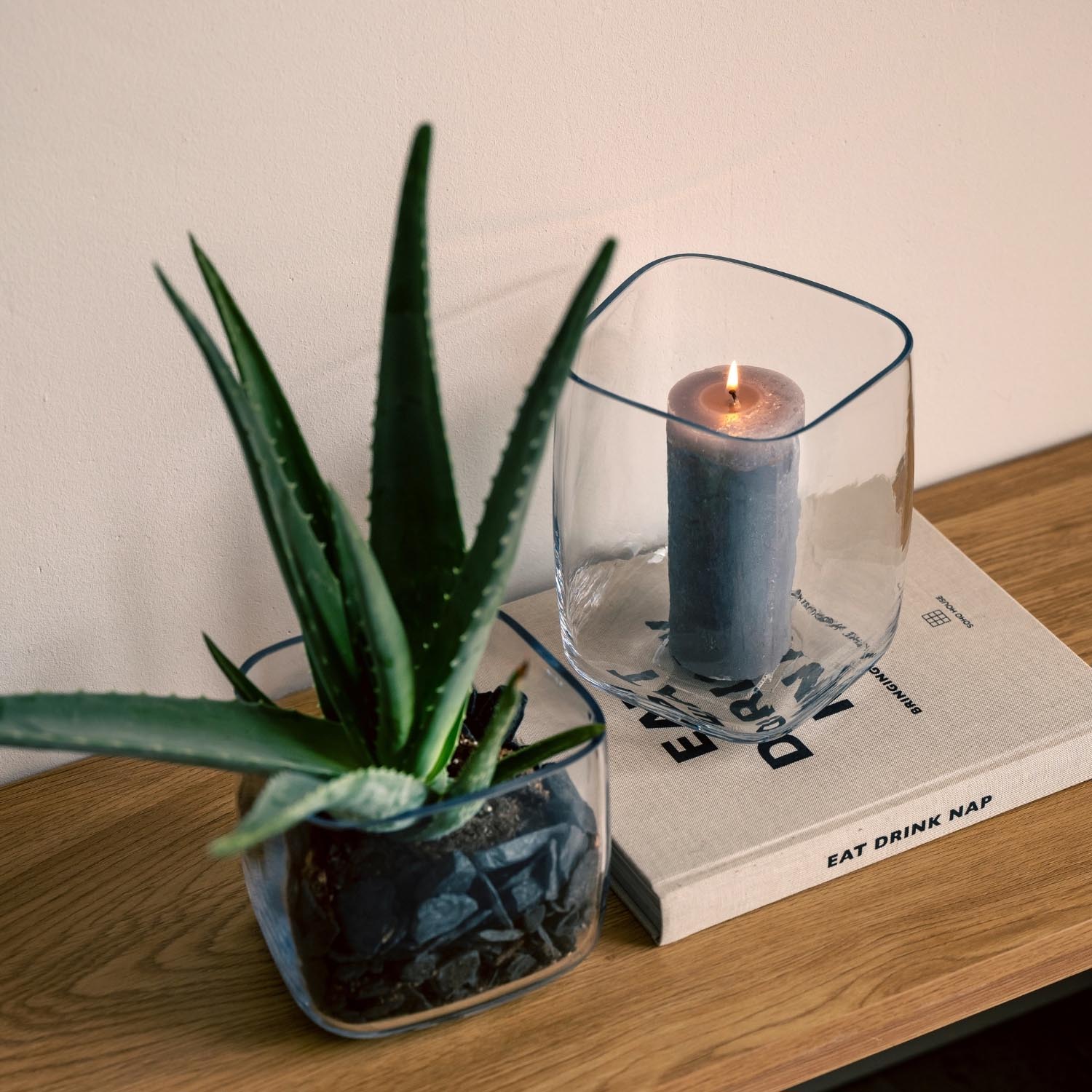 Vase PIETRA mit brennender Kerze, daneben Sukkulente auf Holztisch
