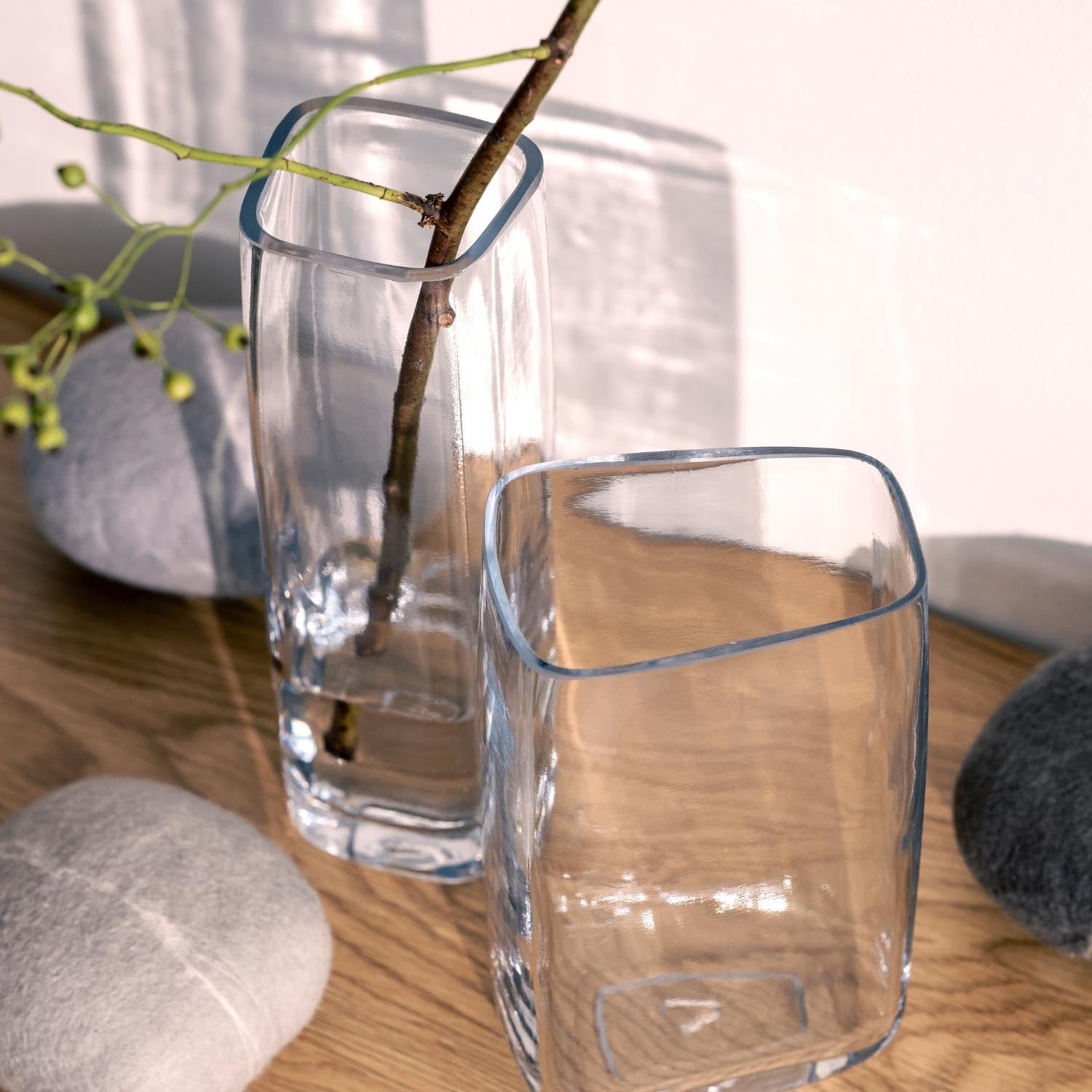 Solifleurvase PIETRA auf Holztisch mit Ast und Wasser, daneben Dekoobjekte