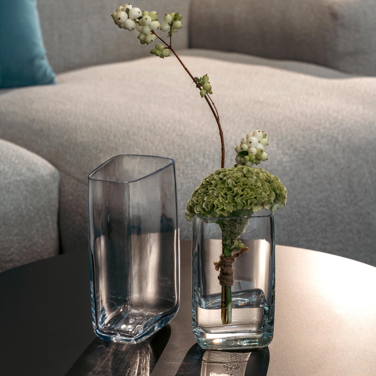Vase PIETRA mit grünen Blüten in Wohnzimmer auf Tisch neben leerem Glas