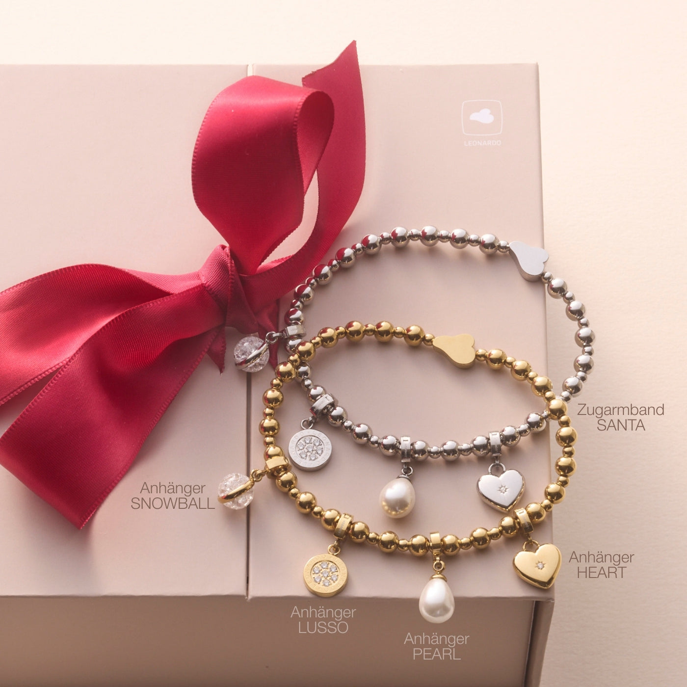 Zwei Perlbrandarmbänder mit Charms wie Herz und Schneeflocke, rote Schleife, Pastellhintergrund