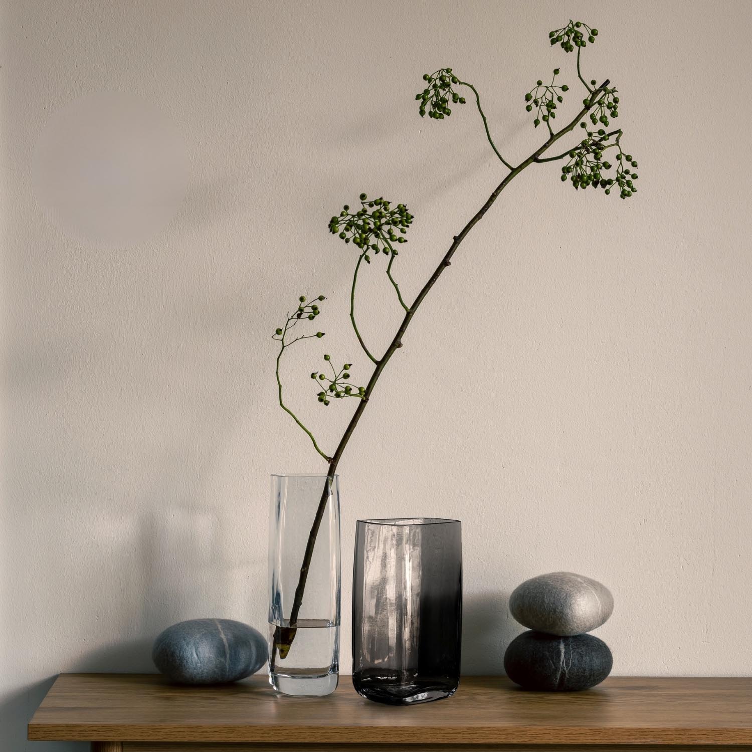 Vase PIETRA 20 cm schmal grau mit Zweig und grünem Laub, neben Steinen auf Holztisch