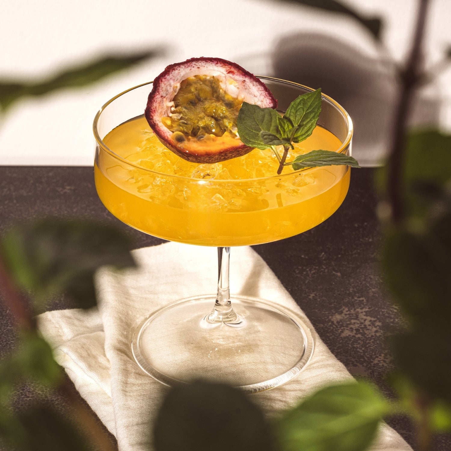 Pornstar Martini angerichtet mit einer aufgeschnittenen Passionsfrucht und einem Minzzweig in der BASSO Schale