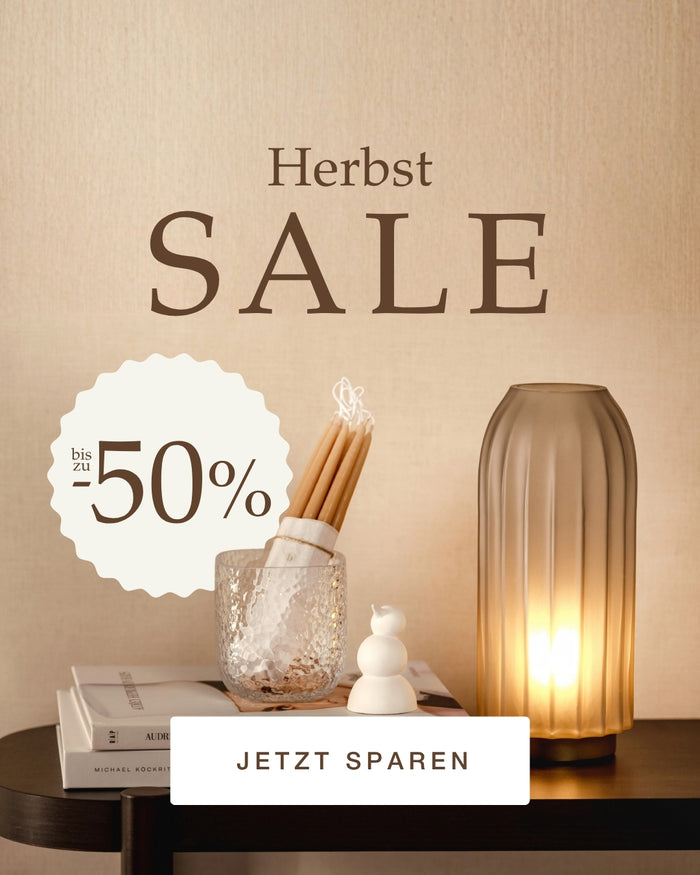 Herbst SALE bis zu -50%, Kerzenhalter und Vase mit warmem Licht auf dunklem Tisch, Jetzt Sparen