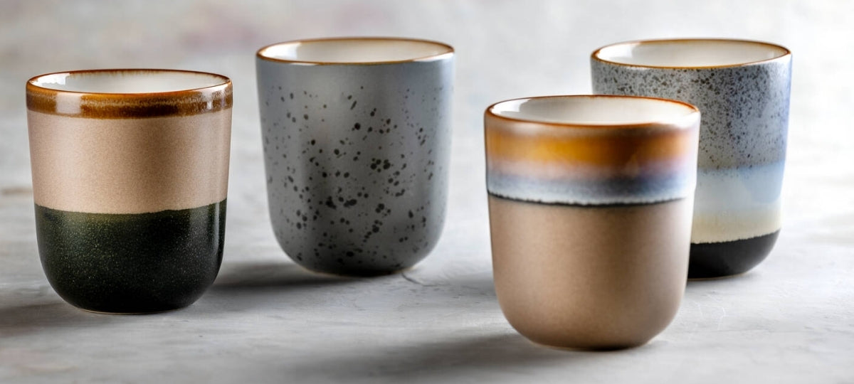 Vier moderne Keramiktassen in Creme, Grau und Schwarz mit geometrischen Farbverläufen auf Marmortisch