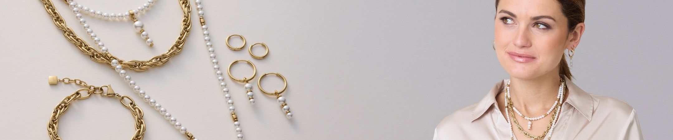 Goldene Ketten, Armbänder, Ringe und Ohrringe kombiniert mit weißen Perlen liegen auf hellem Untergrund. Rechts trägt eine Frau die Schmuckstücke – elegante Kombination aus Gold und Perlen in modernem Stil.