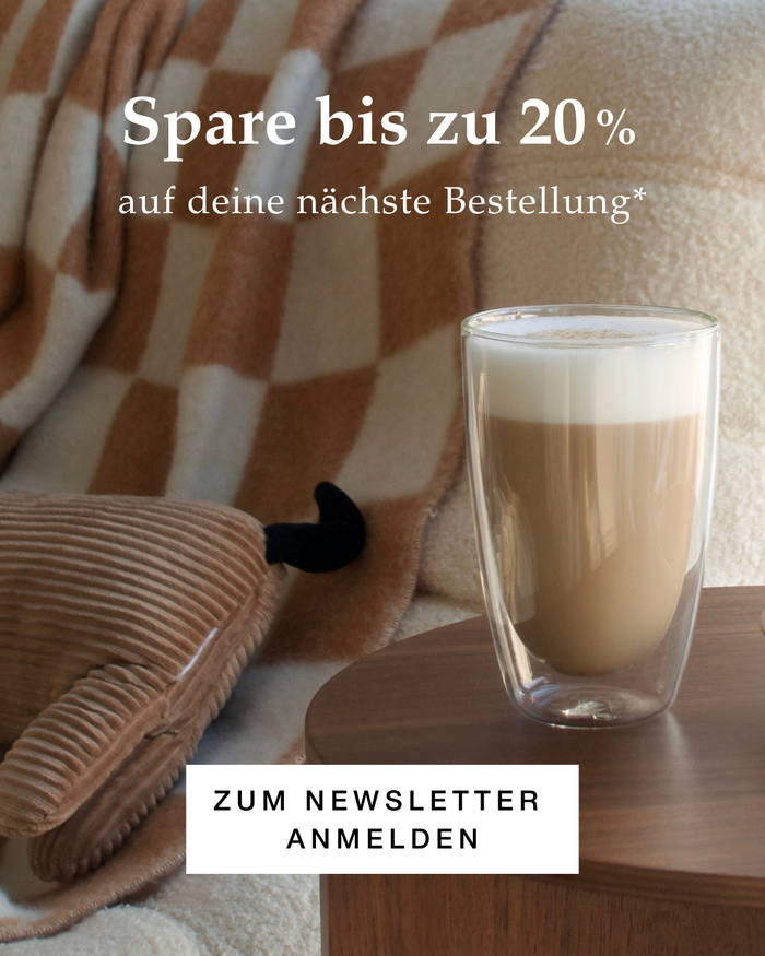 Spare bis zu 20% auf deine nächste Bestellung. Newsletter-Anmeldung. Latte-Macchiato im Doppelwandglas auf Holztisch, gemütliche Wohnzimmeratmosphäre mit Kuscheldecke