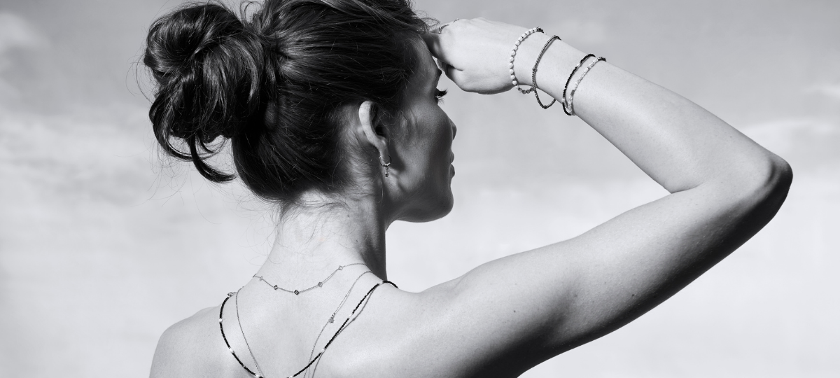 Nahaufnahme von Armbändern und Halsketten mit Perlen und runden Anhängern in Gold und Silber auf hellem Hintergrund.