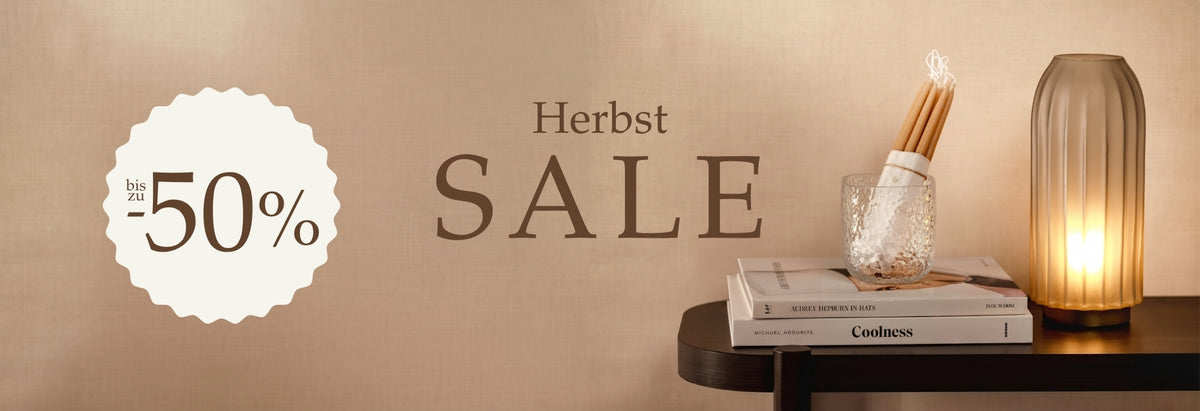 Herbst SALE bis zu 50% Rabatt. Stillleben mit Glasprodukten, Büchern und goldener Leuchte auf warmem Beige-Hintergrund