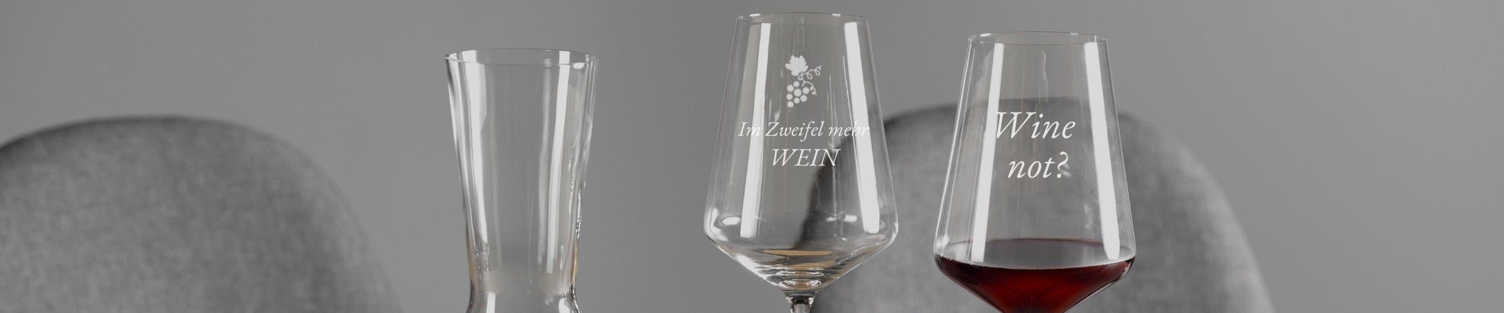 Zwei Weingläser von LEONARDO mit den Sprüchen „Im Zweifel mehr WEIN“ und „Wine not?“ neben einer eleganten Karaffe auf gedecktem Tisch.